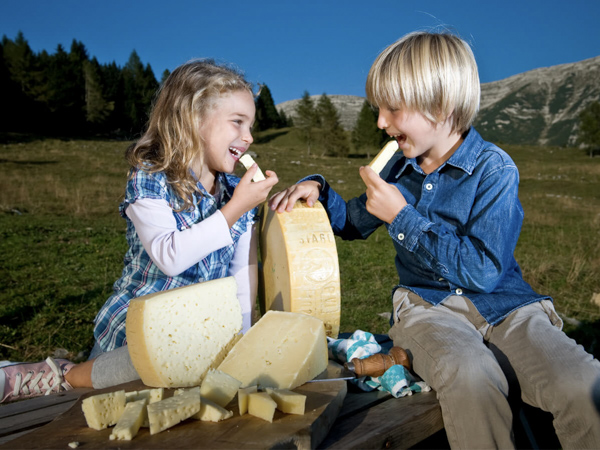 Kinder essen Asiago Dop Käse auf dem Plateau