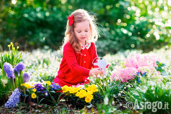 Bambina che osserva e annaffia i fiori