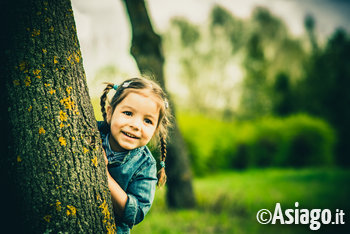 Bambina che spunta da un albero