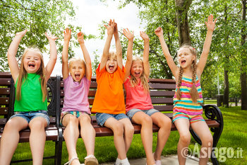 Bambini che esultano seduti su una panca al parco