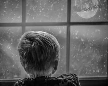 Bambino alla finestra guarda Babbo Natale sulla slitta