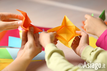 mani di adulto e bambini che fanno origami