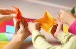 Mani di adulto e bambini che fanno origami