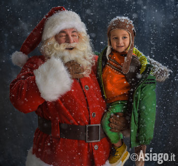 babbo natale con bambino in braccio ride mentre nevica