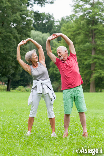 Uomo e donna che fannno esercizi di stretching in piedi all'aperto